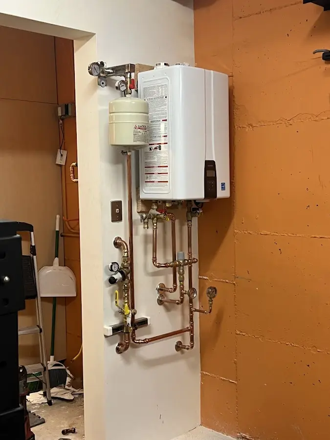 Plumbing technician inspecting water heater connections in Tolleson